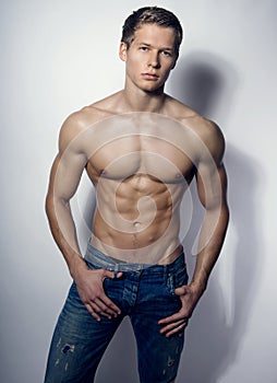 Handsome muscular young bodybuilder showing his muscles and abs