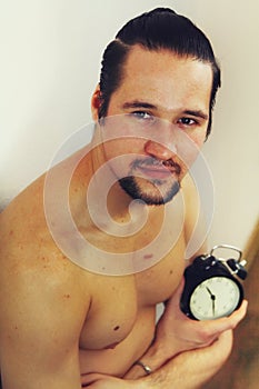 Handsome, muscular young man holding a clock