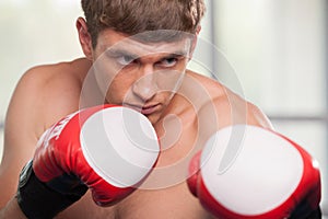 Handsome muscular young man wearing boxing gloves.