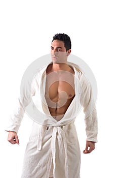 Handsome muscular young man wearing white bathrobe, isolated