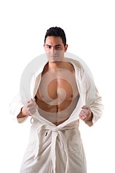 Handsome muscular young man wearing white bathrobe, isolated