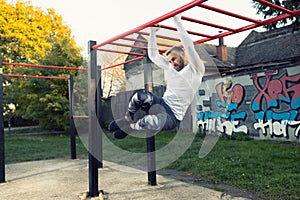 Handsome muscular young man working out under the open sky