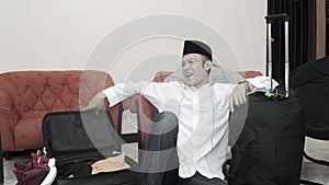 Handsome muslim asian man with traditonal songkok or head cap prepare suitcase luggage for eid mubarak holiday