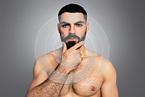Handsome naked middle eastern young man touching his thick beard