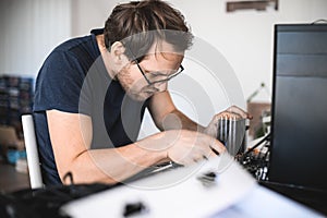 Handsome nerd man is servicing Computer motherboard and cooler.