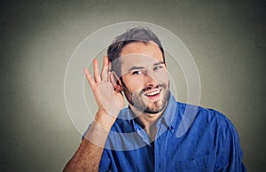 Handsome nosy business man secretly listening in on conversation, hand to ear