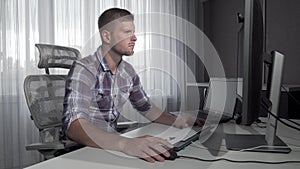 Handsome IT office worker using two computers working on a project