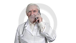 Handsome old doctor talking on the phone with one of his patients.