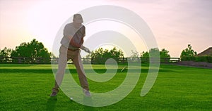 Handsome older golfer swinging golf club, golfing in paradise.