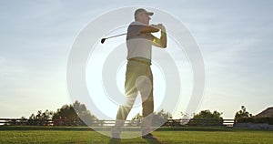 Handsome older golfer swinging golf club, golfing in paradise.