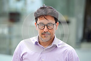 Handsome older man with glasses standing and thinking outdoors