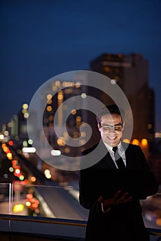 Handsome Persian businessman against view of the city at night