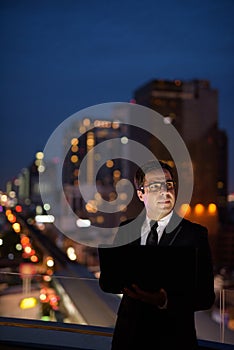 Handsome Persian businessman against view of the city at night
