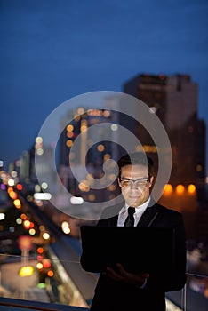 Handsome Persian businessman against view of the city at night