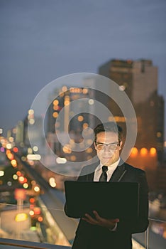 Handsome Persian businessman against view of the city at night