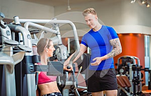 Handsome personal trainer guiding a beautiful woman at a modern fitness