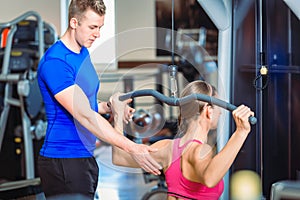 Handsome personal trainer guiding a beautiful woman at a modern fitness club