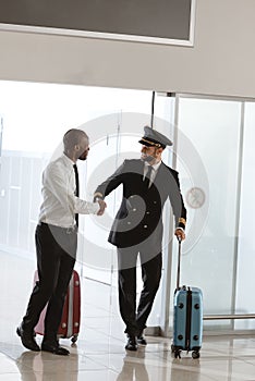 handsome pilot handshaking with young businessman