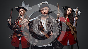 Handsome pirate with flintlock pistol and two female buccaneers