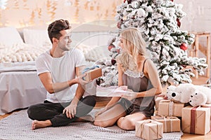 Handsome pleasant man giving a Christmas gift to his girlfriend