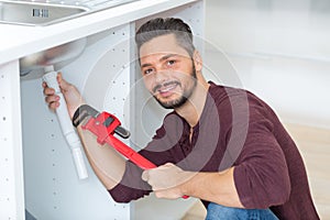 handsome plumber repairing sink pipes in bathroom