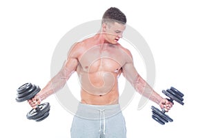 Handsome power athletic man with dumbbell confidently looking forward. Strong bodybuilder with six pack, perfect abs