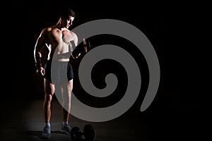 Handsome power athletic man training pumping up muscles with dumbbells.