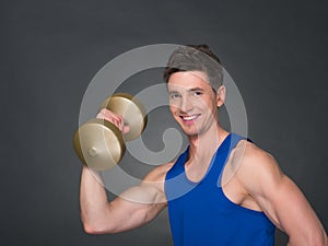 Handsome power athletic man in training pumping up muscles with dumbbells in a gym.