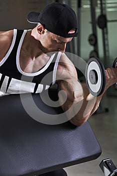 Handsome powerful athletic man doing biceps exercise with dumbbell