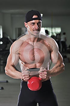 Handsome powerful athletic man doing biceps exercise with kettle bell