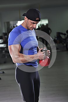 Handsome powerful athletic man doing biceps exercise with kettle bell