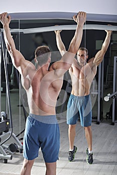 Handsome powerful athletic man doing pull-ups. Strong bodybuilder with perfect abs, back and chest.