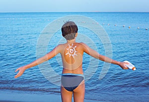 Handsome preteen boy with anti sunburn cream sun drawing on his