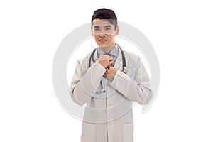 Handsome pretty brunette male doctor in uniform with stethoscope on his neck posing on camera isolated on white