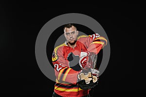 handsome professional ice hockey player standing with sports equipment and looking at camera