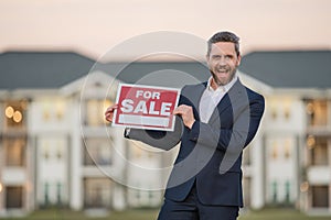 Handsome real estate agent holding banner house for sale. House with land and insurance. Man real estate agent in