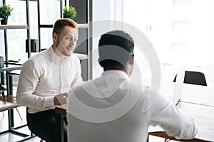 Handsome red-haired businessman talking to African American business partner about new project