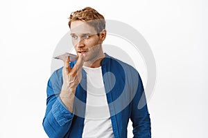 Handsome redhead man record voice message, holding smartphone near lips as translating his words in cellphone app, using