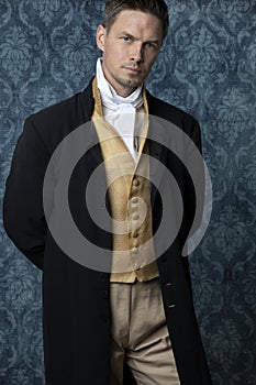 A handsome Regency gentleman wearing a gold waistcoat, breeches, and a black coat