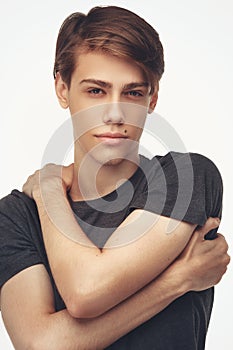 Handsome relaxed man in t-shirt. Portrait of young seductive guy, looking at camera, white studio background. Posing for