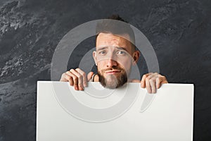 Handsome sad man holding white paper in studio