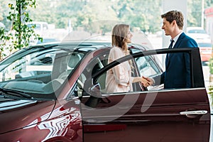 Handsome sales Manager shaking hands to customer after selling a car