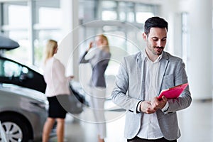 Handsome salesman at car dealership selling vehichles