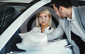 Handsome salesman at car dealership selling vehichles