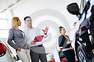 Handsome salesman at car dealership selling vehichles