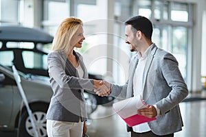 Handsome salesman at car dealership selling vehichles