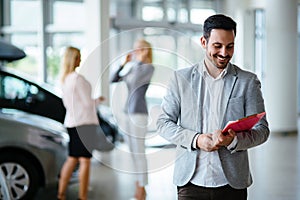 Handsome salesman at car dealership selling vehichles