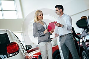 Handsome salesman at car dealership selling vehichles