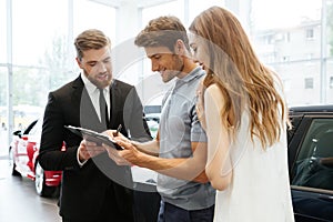 Handsome salesman filing documents with his happy clients