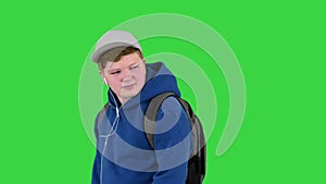 Handsome school boy walking by while listening to music on a Green Screen, Chroma Key.